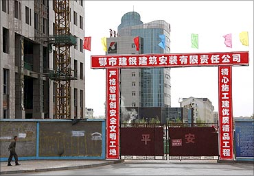 一名男子从未完工的房子前走过 一名男子从未完工的房子前走过